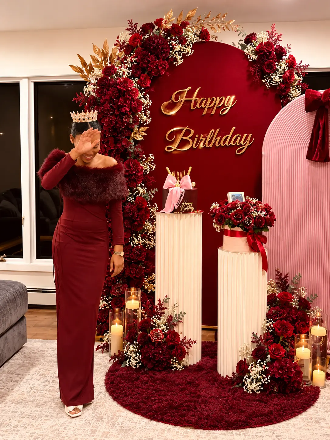 Burgundy and pink birthday backdrop with red roses, gold lettering, pedestals and candles