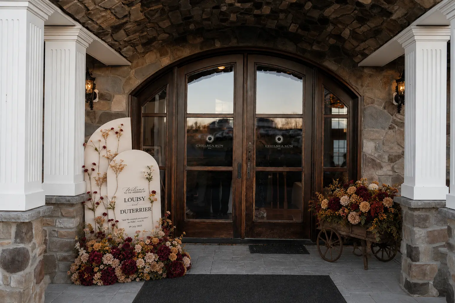 Wedding entrance styling with arched welcome signage, autumn floral ground arrangement and a floral filled wooden cart