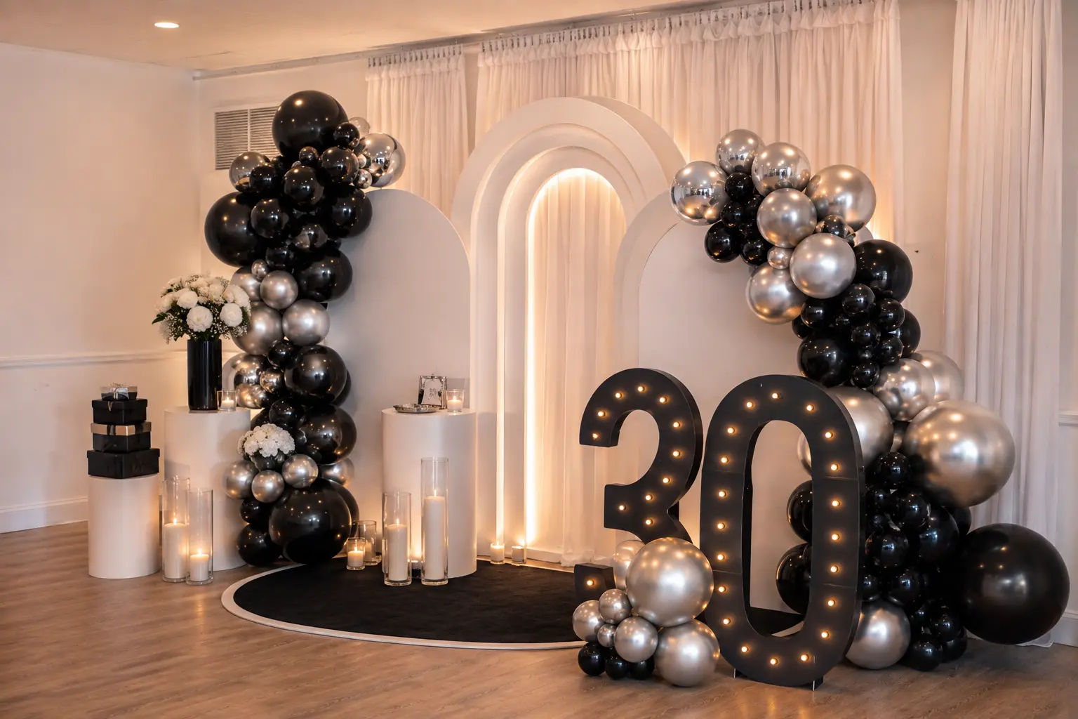 Black and silver birthday backdrop with balloon garlands, candles and illuminated marquee number thirty