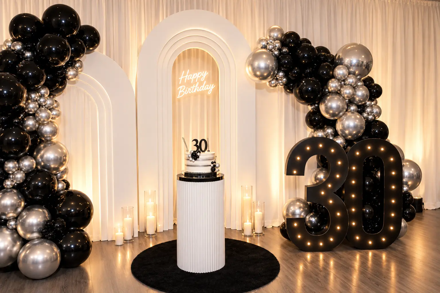 Black and silver 30th birthday setup with balloon garland, arched backdrops, cake pedestal and lit marquee numbers